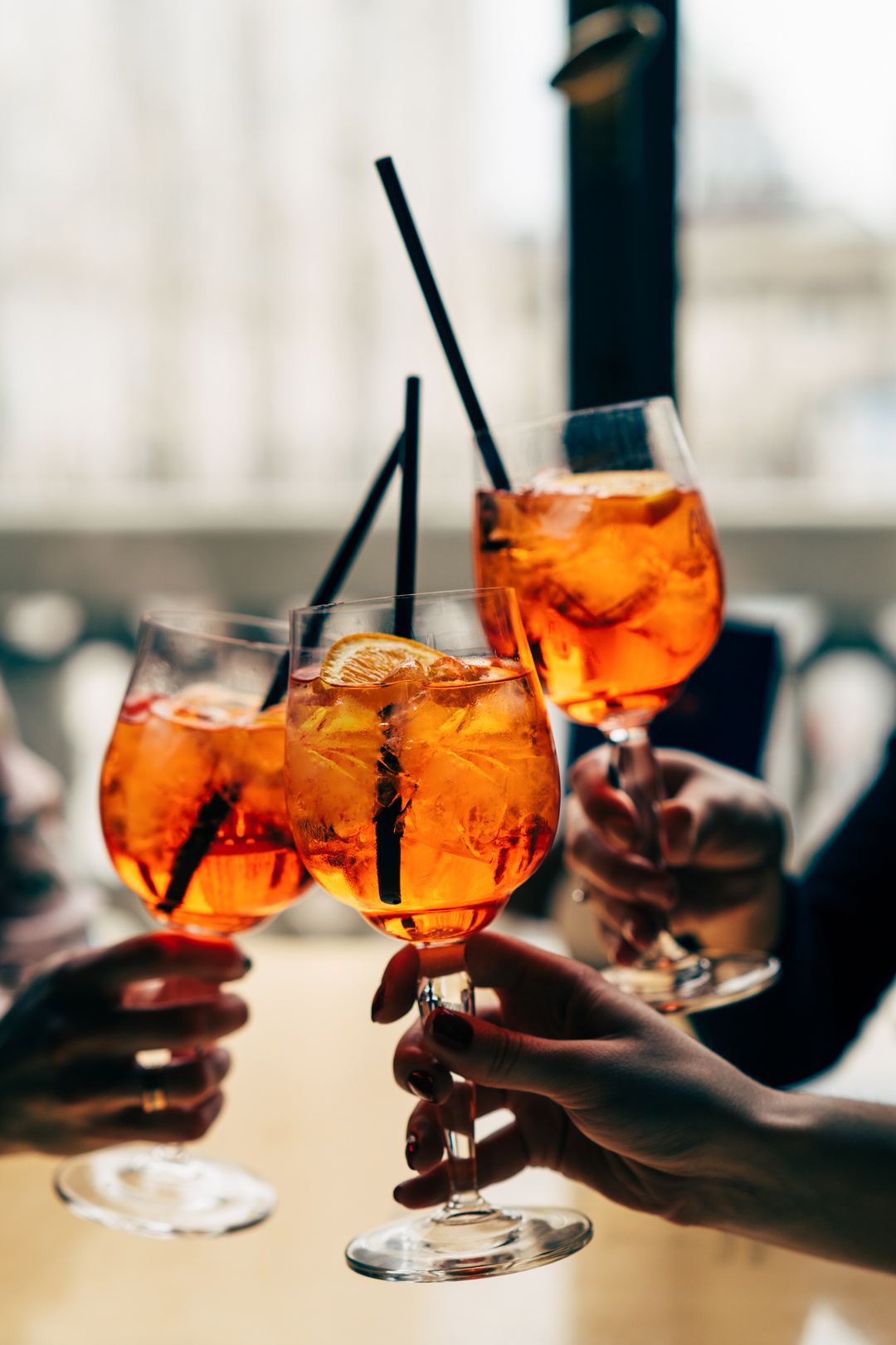 Making a celebratory toast with aperol spritz cocktails. Friends toasting with summer cocktails